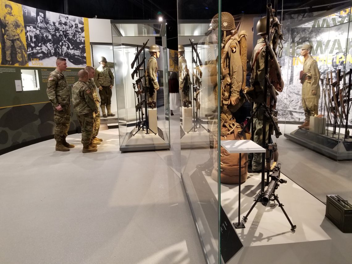 Three people looking at museum exhibits inside the Don F. Pratt Museum.